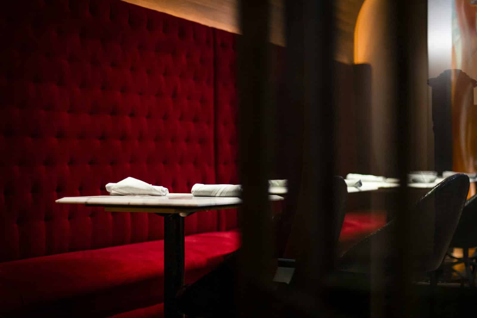 Dæmpet lounge med rød velourbænk og borde – stemning som i en swingerklub
